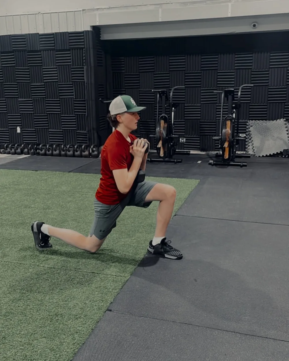 An adult member holding a split squat on the turf
