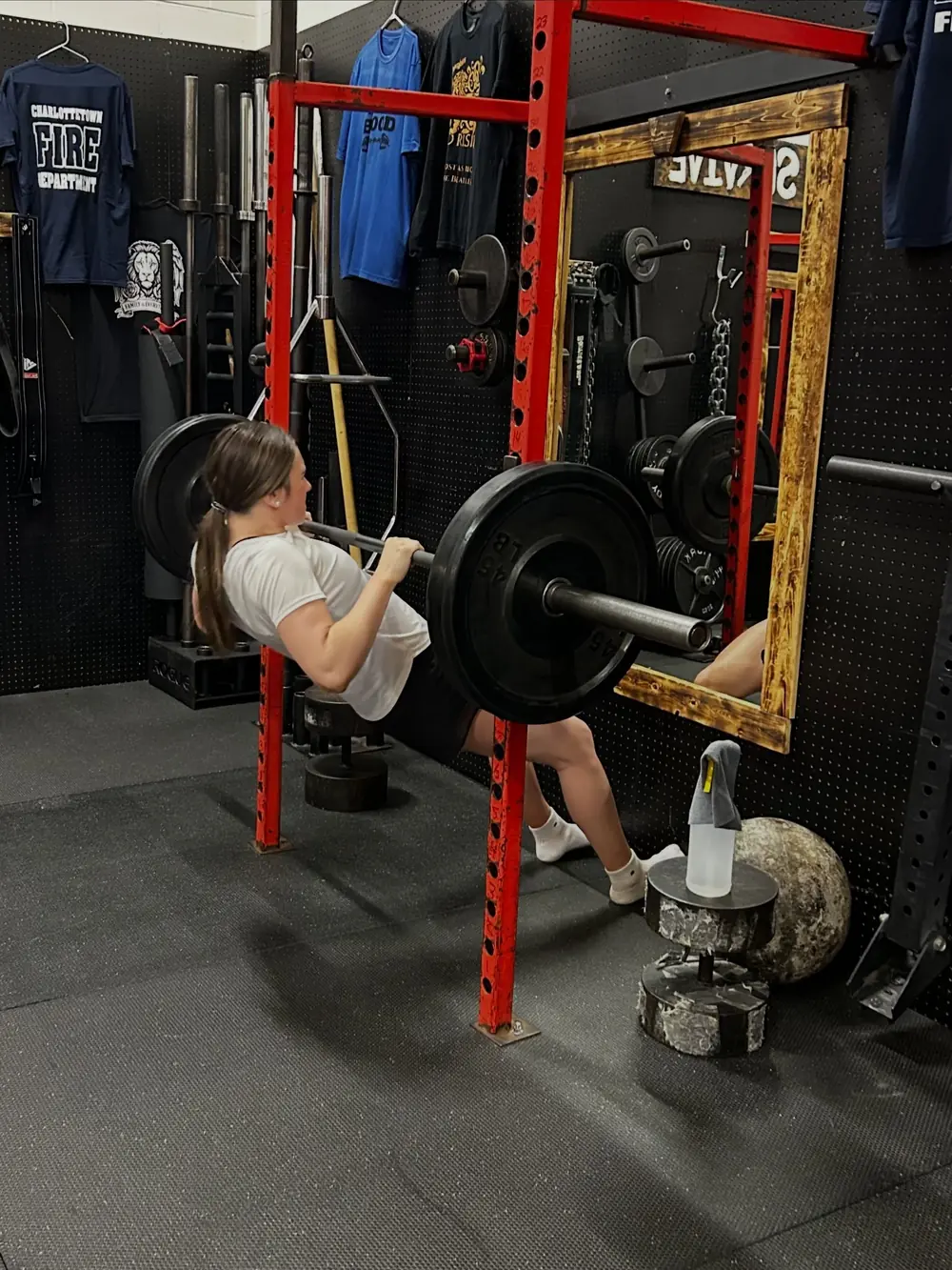 A young athlete squatting in the rack with a coach watching